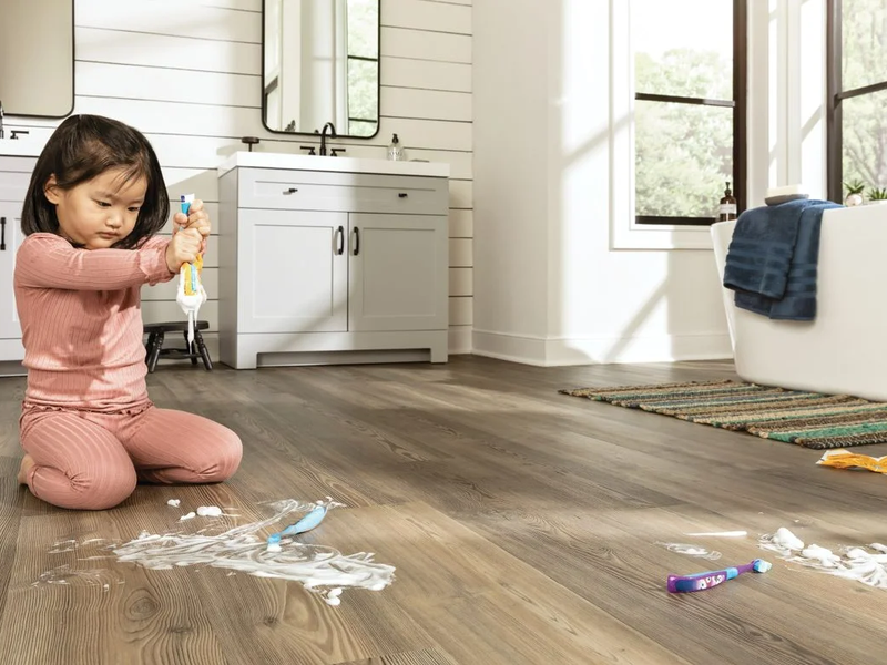 A child squeezes a tube of toothpaste on a Mohawk spillproof lvt bathroom floor.